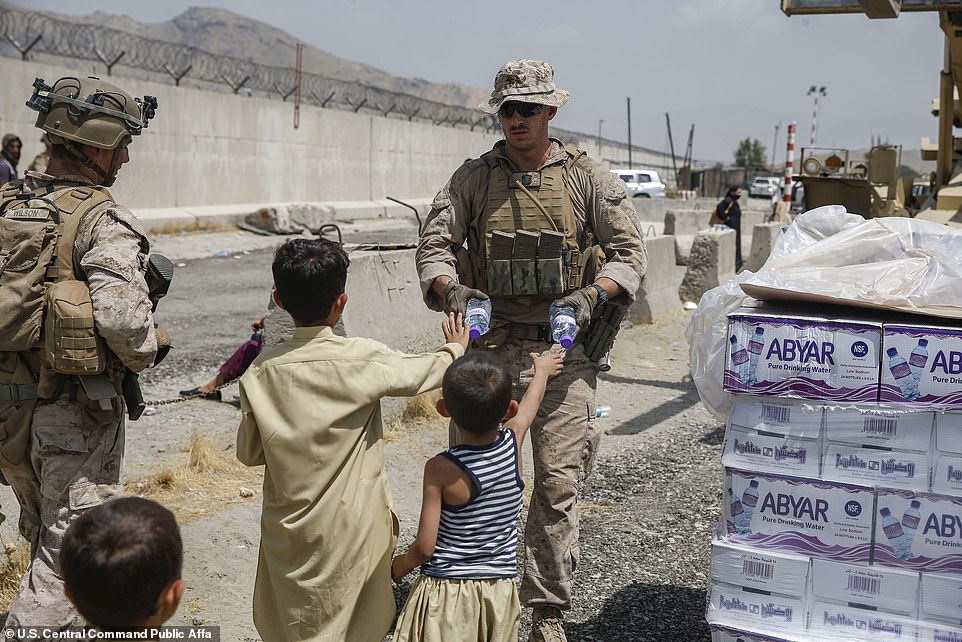 A US Navy corpsman hands out water to children during an evacuation at the airport in Kabul