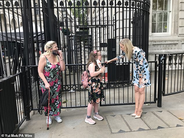 Disability rights activist, Heidi Crowter (centre), with her mother, Liz Crowter (left) and DUP MP Carla Lockhart (right) outside Downing Street, London, whilst a police officer delivers her petition of 18,000 signatures calling for changes to the abortion laws in Northern Ireland