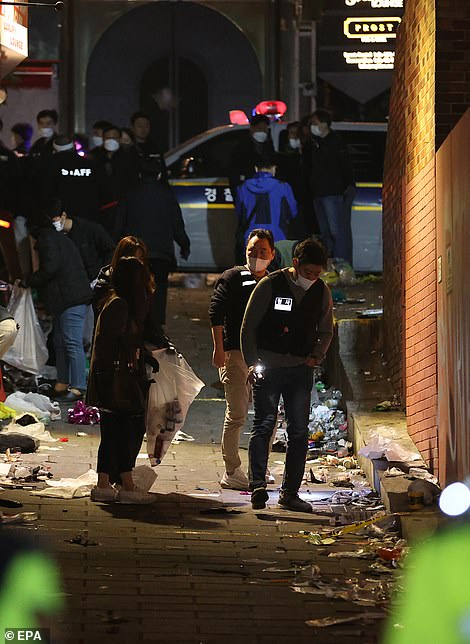 Police officers examine objects on the floor in the aftermath of the crush