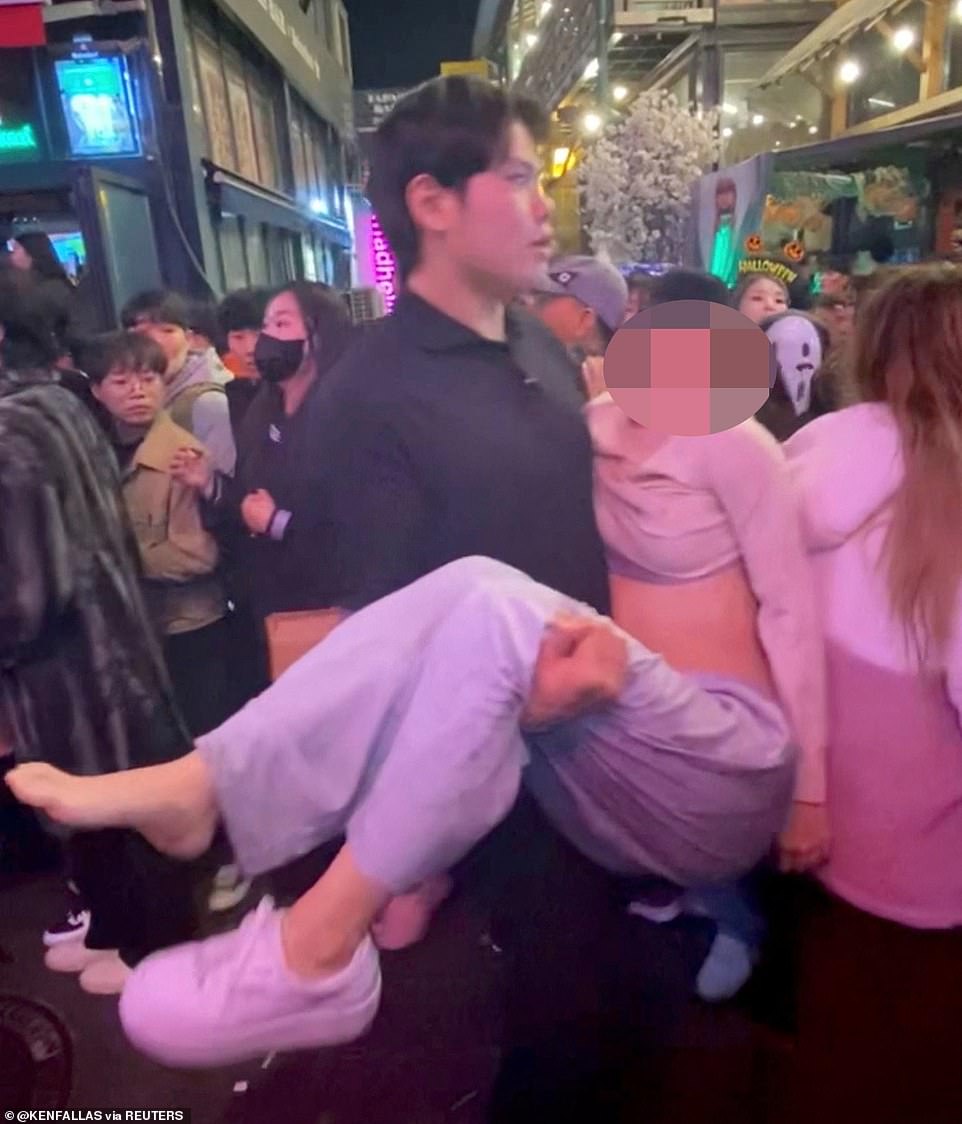 An exhausted young woman is carried away from the scene to safety after becoming caught up in the night's events