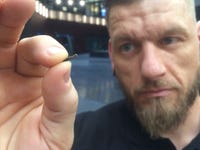 Man holds up a microchip implant the size of a grain.