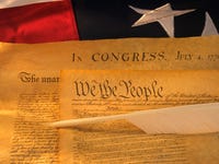 The US Constitution document over an American flag