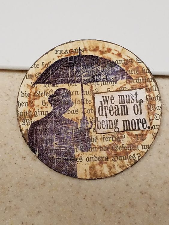 Artist trading coin created with an old bookpage and Tim Holtz stamps and paints.