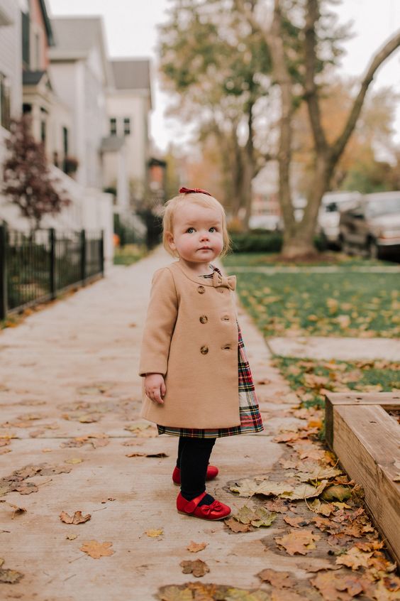 Just the cutest little girl's holiday outfit. Emma is wearing a toddler size camel trench coat, a plaid dress, tights, and red mary jane shoes.