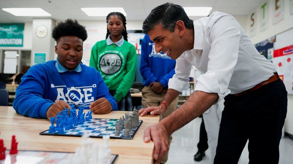Rishi Sunak watches a child playing chess on a visit to a US school in Washington