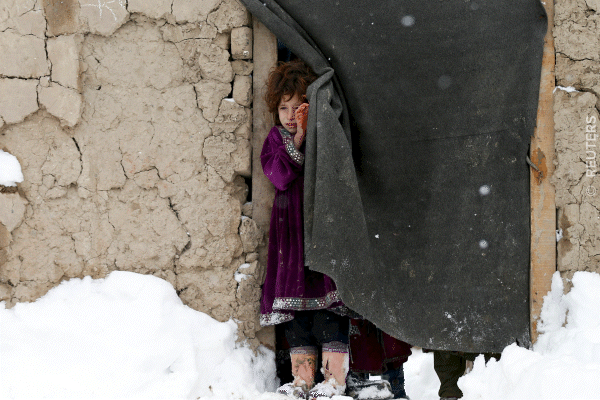 An internally displaced Afghan girl stands at the door of her shelter during a snowfall in Kabul.