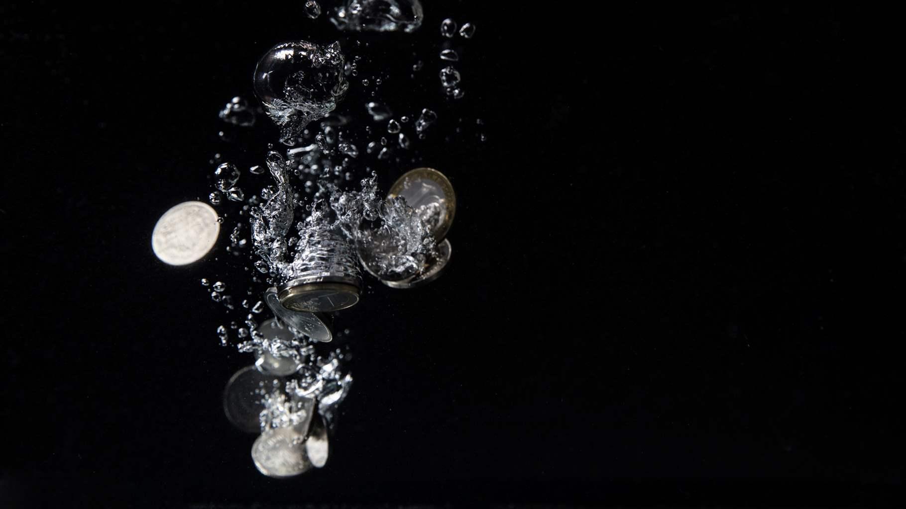 Coins falling through water on a black background. 