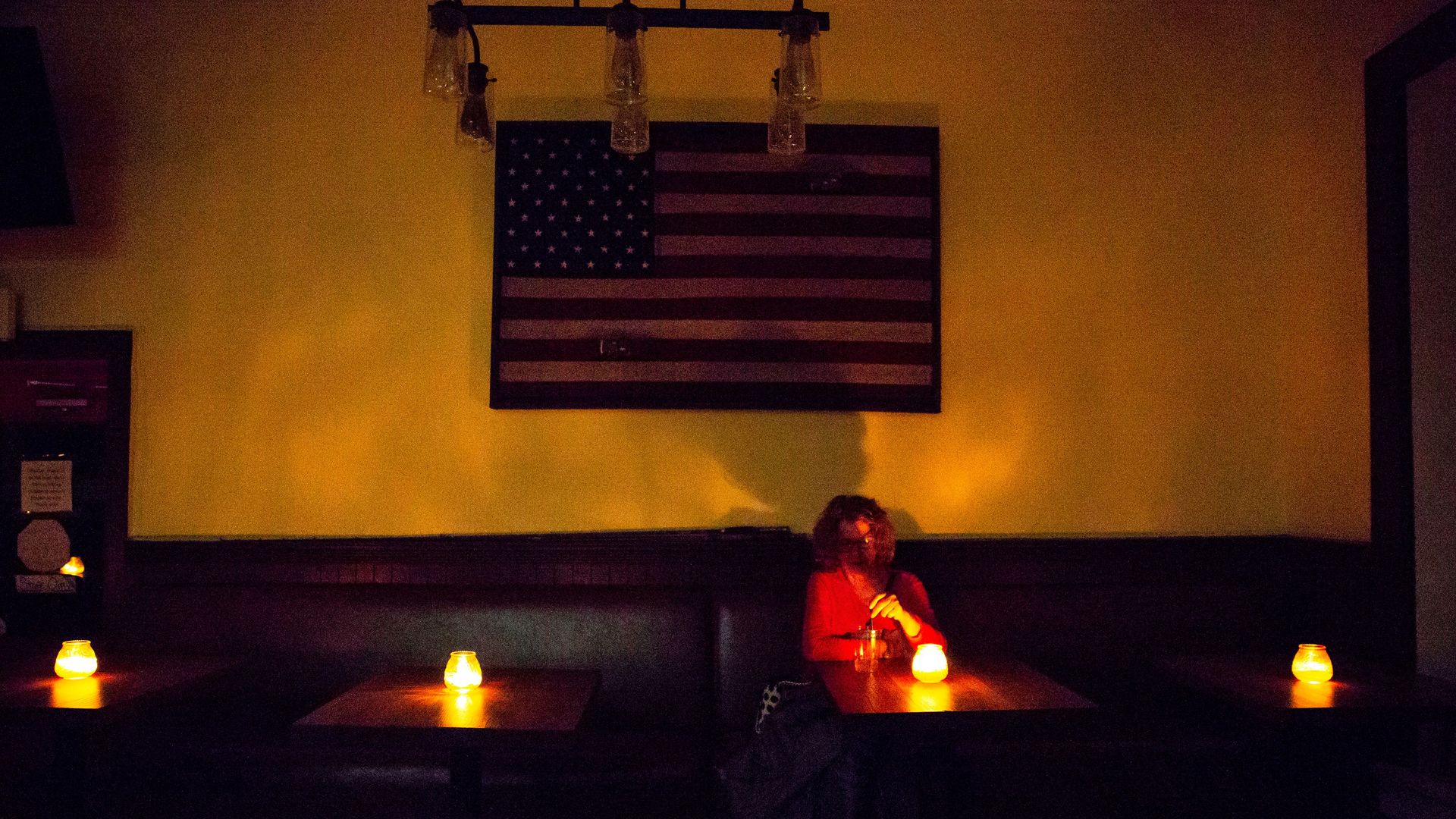 Photo of a person sitting in a California restaurant lit by candlelight during one of PG&E's shut-offs