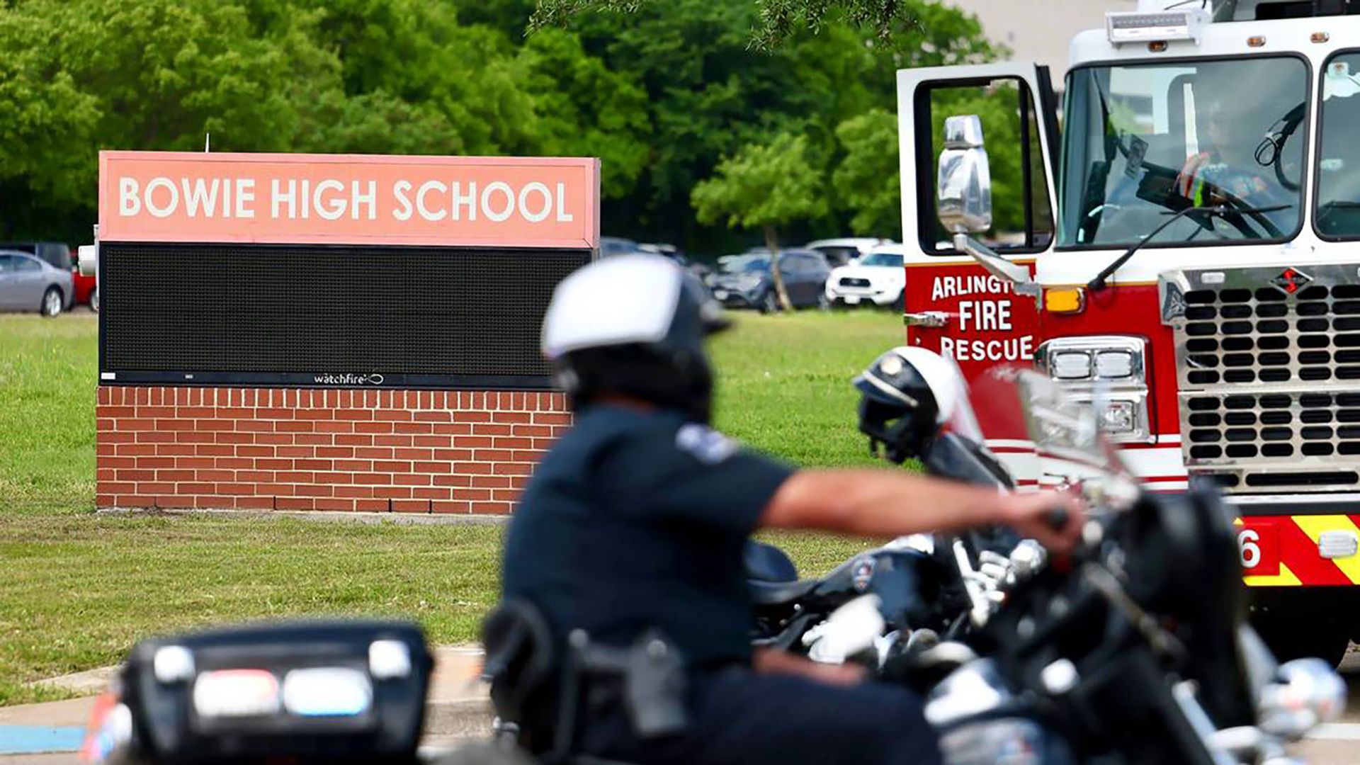a photo of a motorcycle police officer driving by Bowie High School