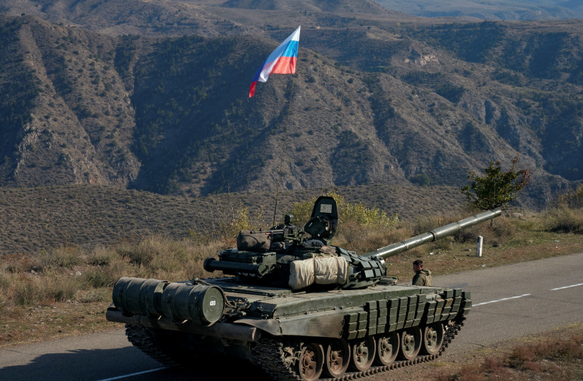 A service member of the Russian peacekeeping troops stands next to a tank near the border with Armenia, following the signing of a deal to end the military conflict between Azerbaijan and ethnic Armenian forces, in the region of Nagorno-Karabakh, November 10, 2020 (photo credit: REUTERS/FRANCESCO BREMBATI)