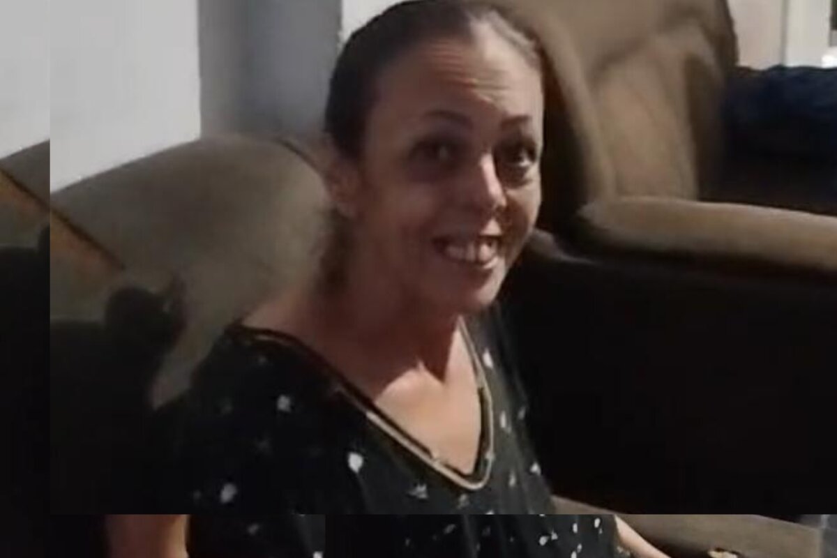 Mulher de meia idade sorri para a câmera, com vestido escuro de bolinhas brancas - Metrópoles