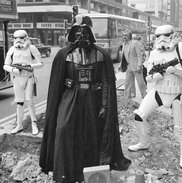  Darth Vader and two stormtroopers from the film 'Star Wars' stand menacingly over some road works in London's Oxford Street in 1980.