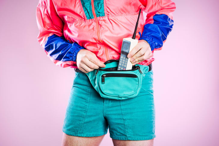 Retro styled man putting a gigantic cell phone into his fanny pack