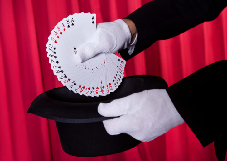 Magician Hand Holding Fanned Deck Of Cards From Hat
