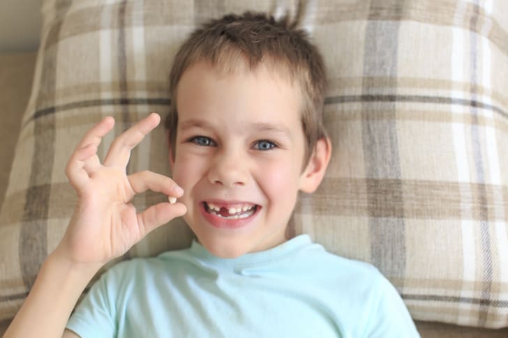 Young boy who has lost a tooth gets ready to put it under his pillow for the Tooth Fairy