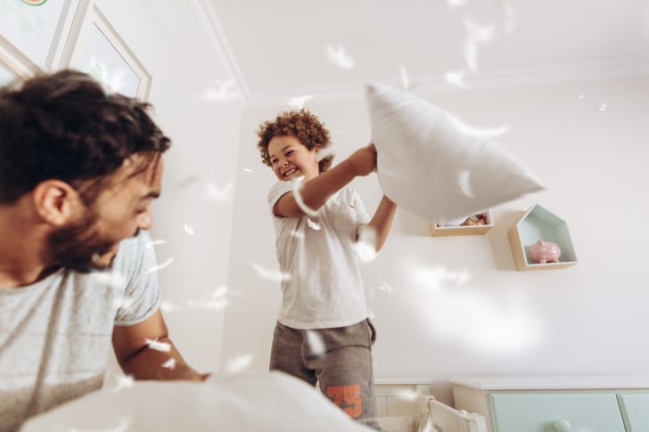 Young boy and his dad having a pillow fight