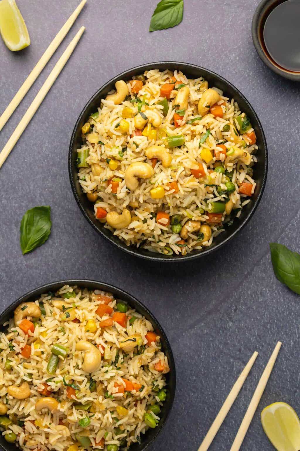 Vegan fried rice in black bowls with chopsticks on the side. 