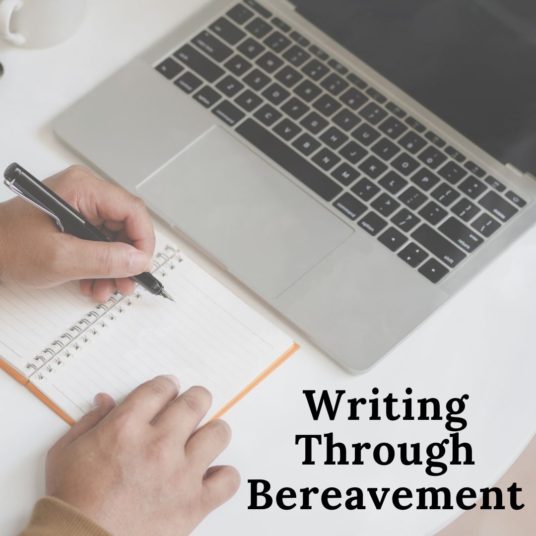 Laptop with person's hand and pen beginning to write in an open notebook with the words Writing Through Bereavement