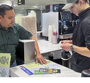A Denver Labor analyst shows minimum wage materials to a food and beverage worker.
