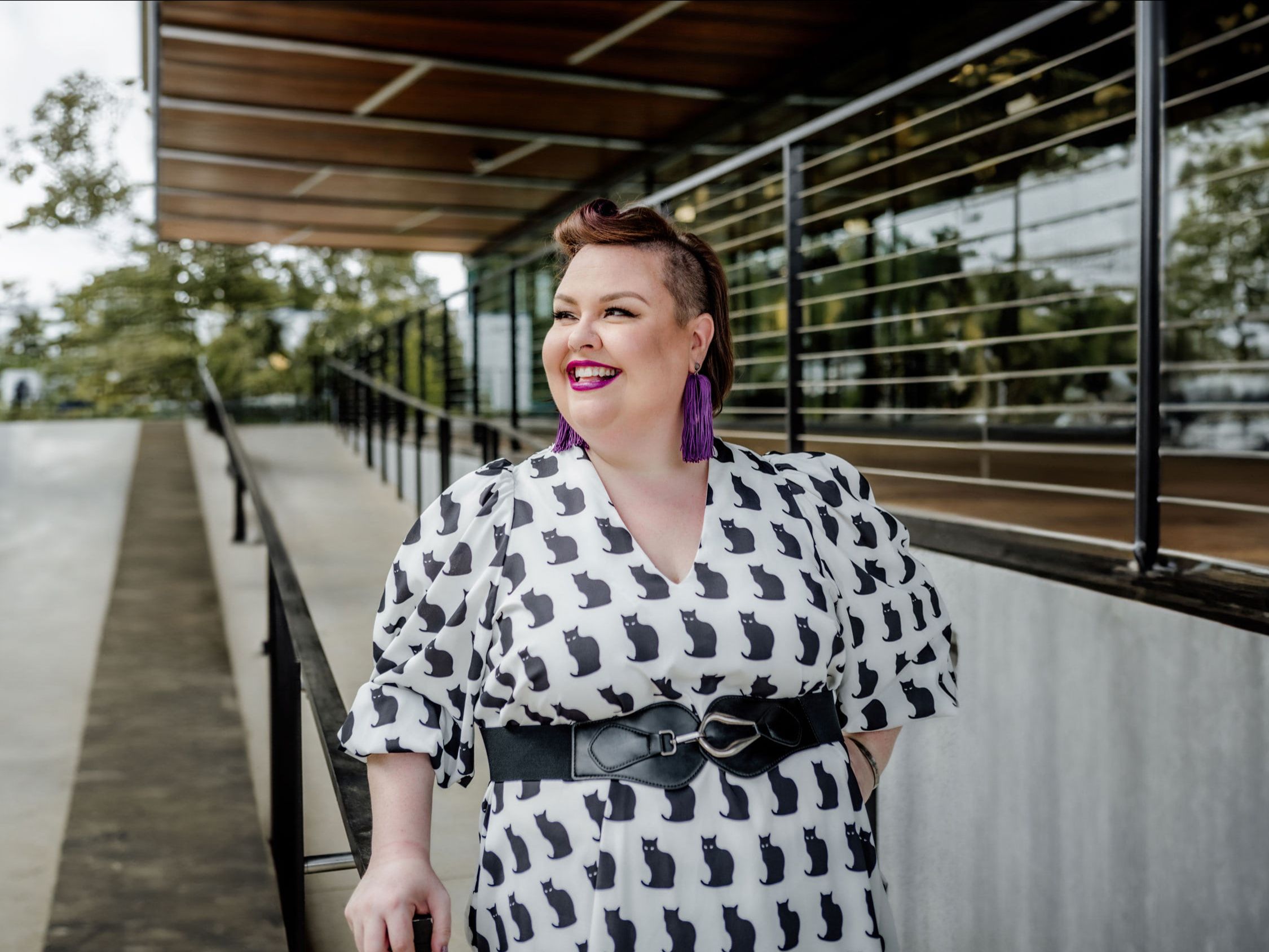 Woman in cat print dress with purple earrings
