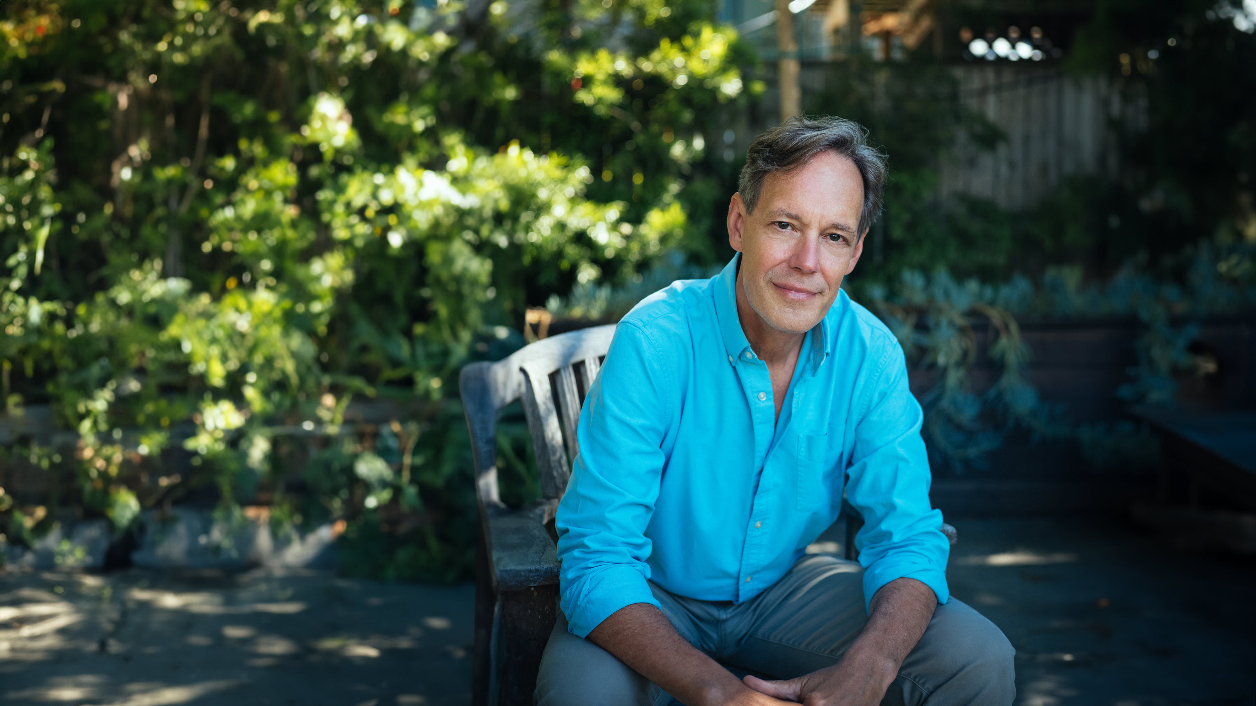 Composer Jake Heggie works on a score at the piano in a sunlit room.