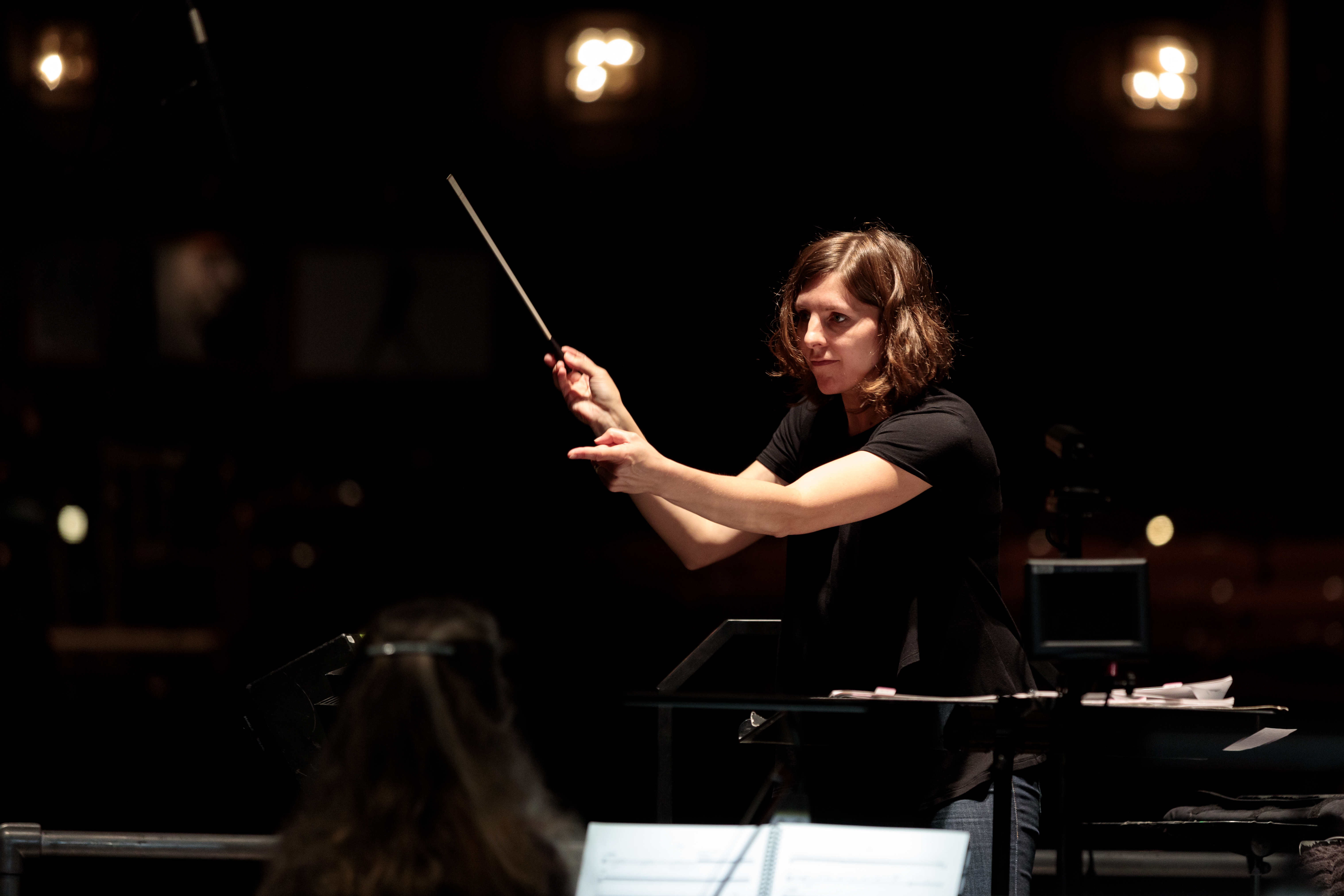 a woman holding a baton conducting an orchestra