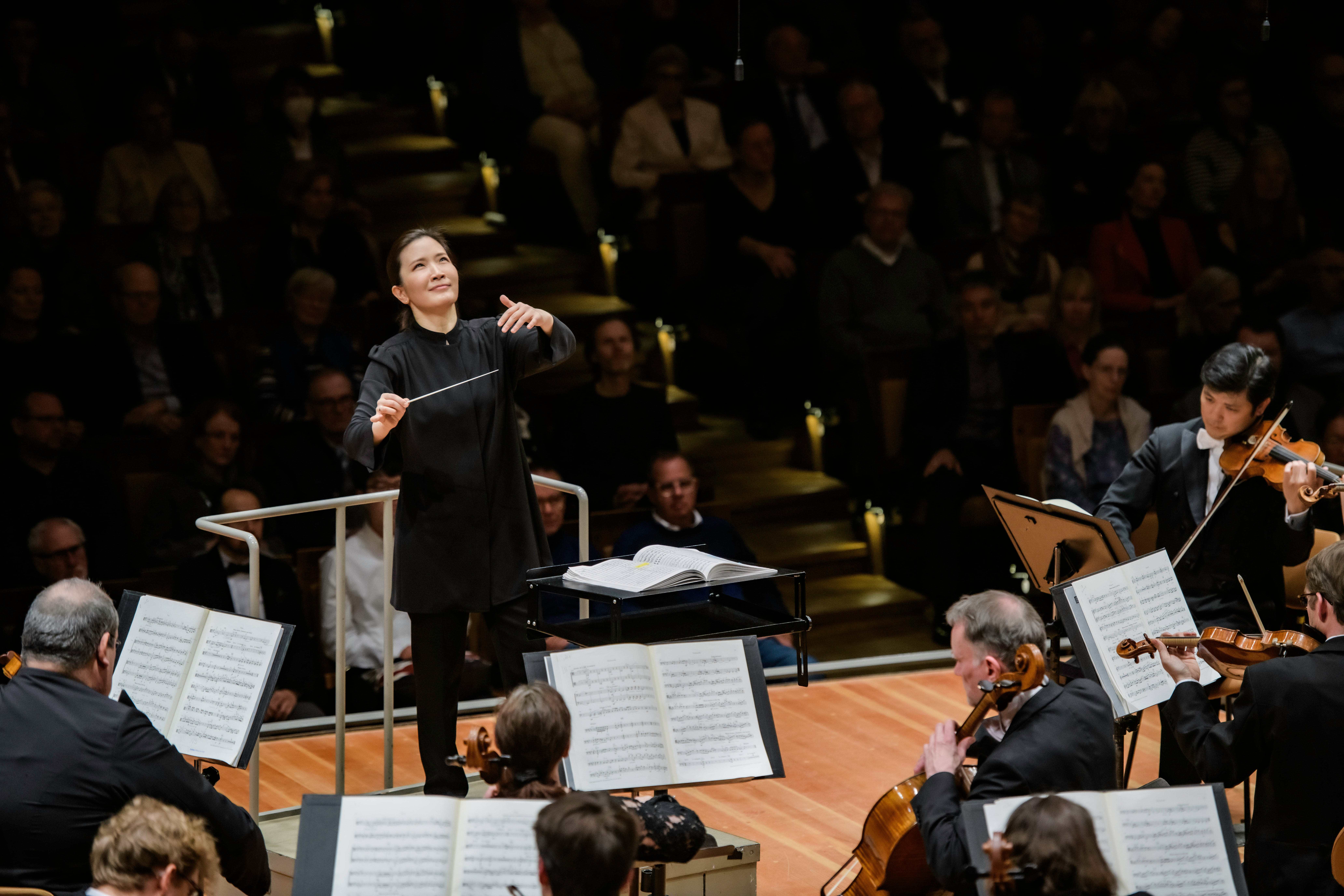 a woman conducting an orchestra in a symphony performance