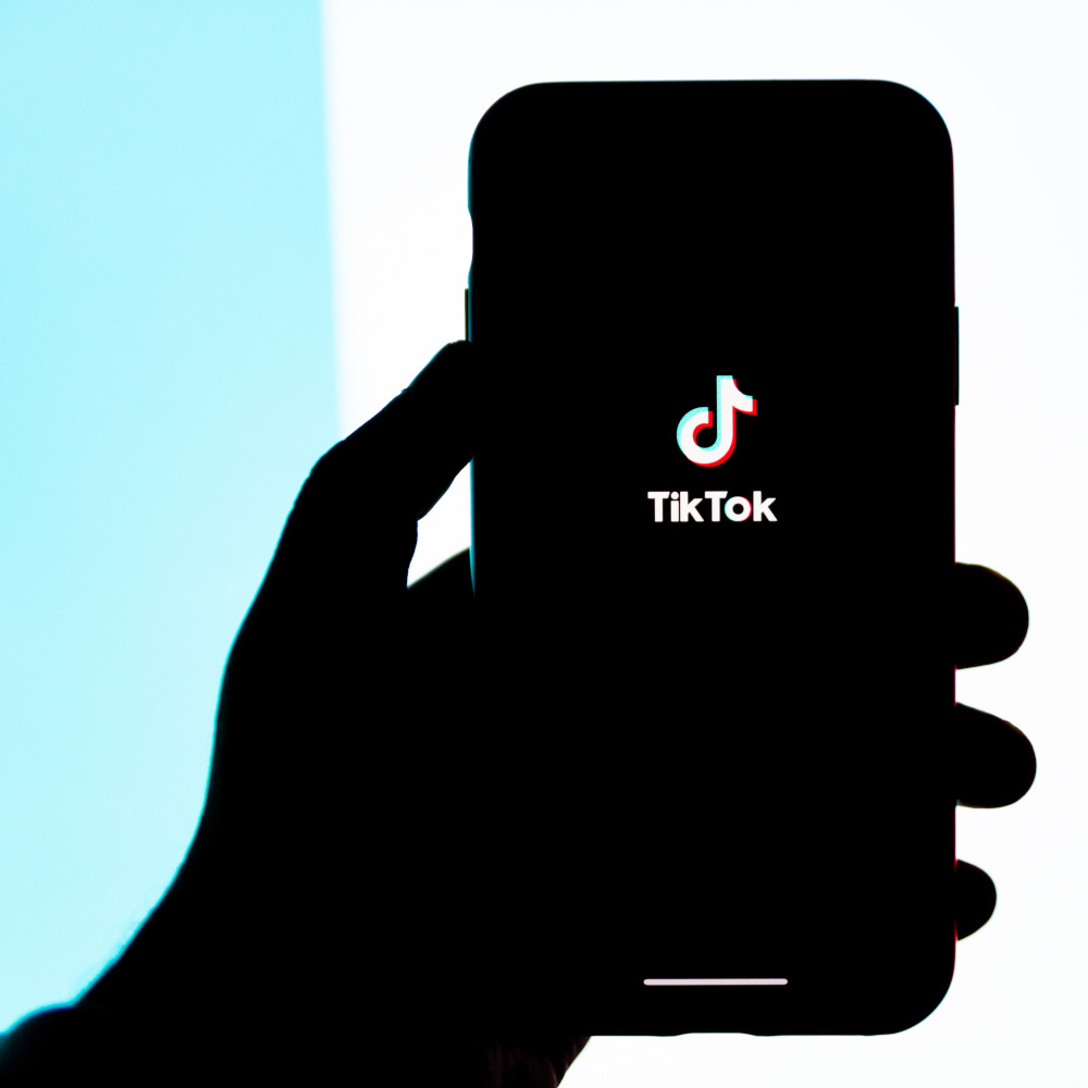 Grafik einer Hand, die ein Smartphone mit TikTok-Symbol hält