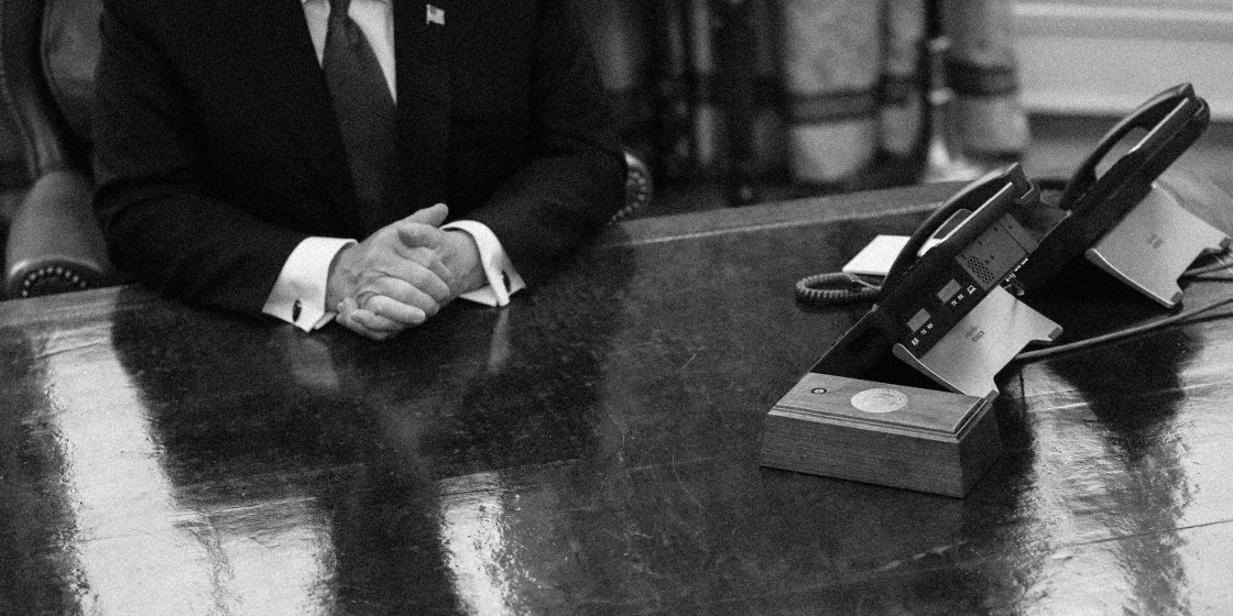 A photo of a Congress member sitting at a desk by their phone