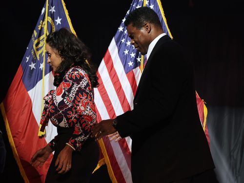 Herschel Walker and Julie Blanchard walk off stage after his concession speech.