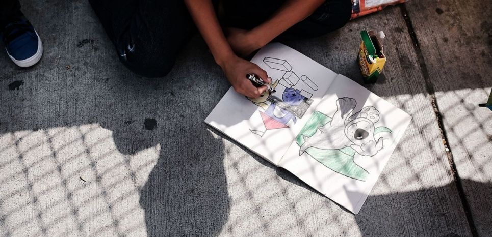 28/06/17 Un enfant hondurien dessine en attendant avec sa famille au niveau du pont frontalier après qu'ils se soient vus refuser l'entrée aux Etats-Unis via Mexico, le 25 juin 2018.
