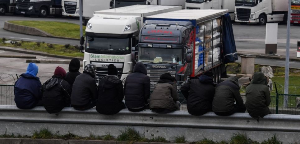 Des migrants assis sur la barrière d'un parking pour camions, le 30 mars 2018 à Calais.