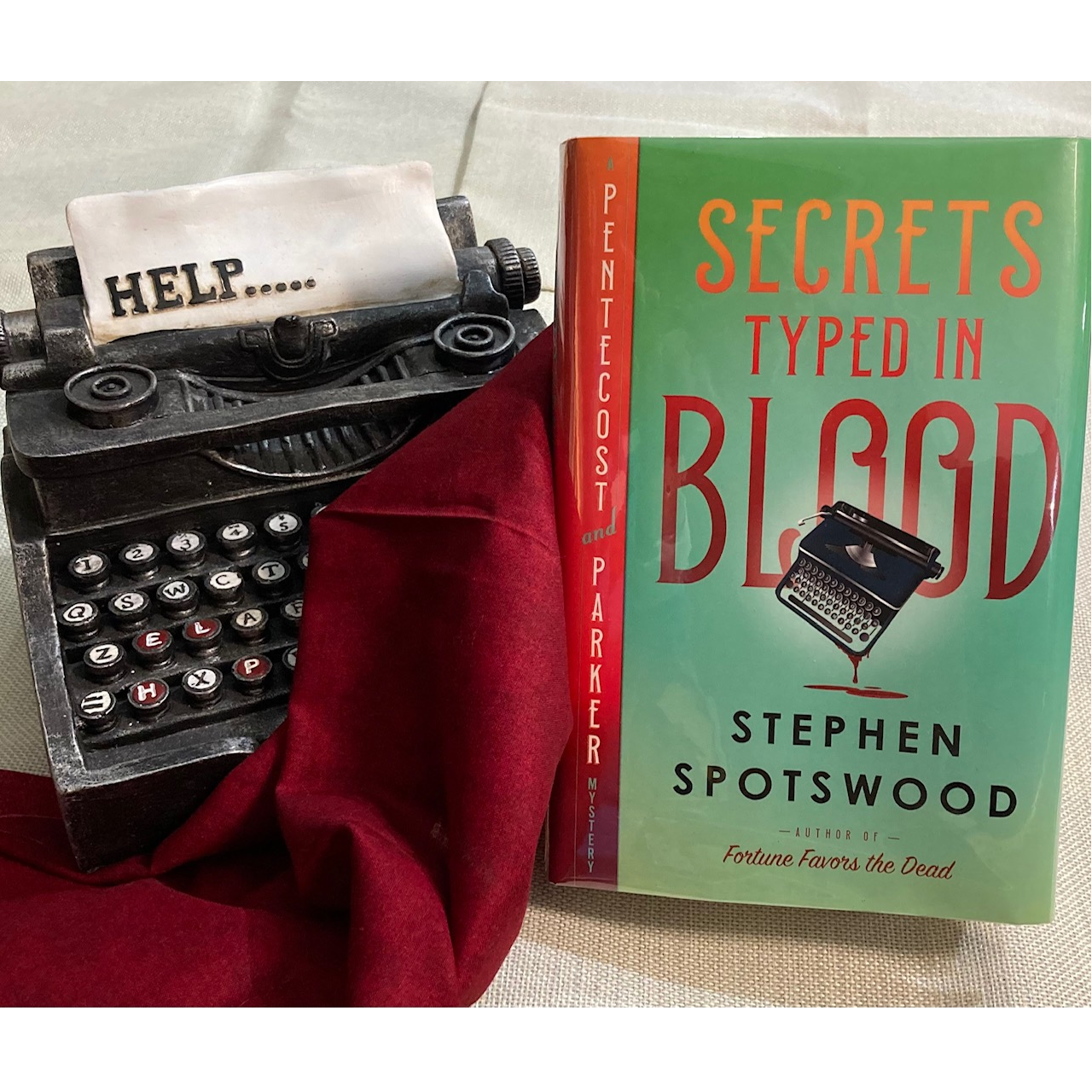 The book Secrets Typed in Blood next to a typwriter typing Help The book Secrets Typed in Blood next to a typwriter typing Help