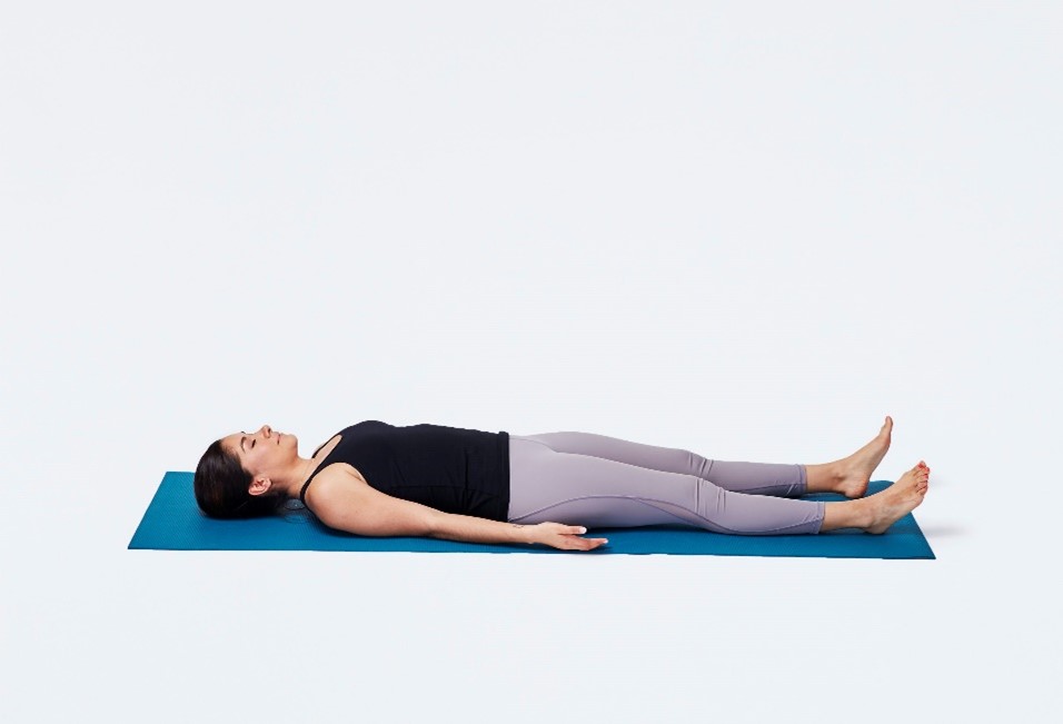 Woman in savasana (or corpse pose) on a blue yoga mat.