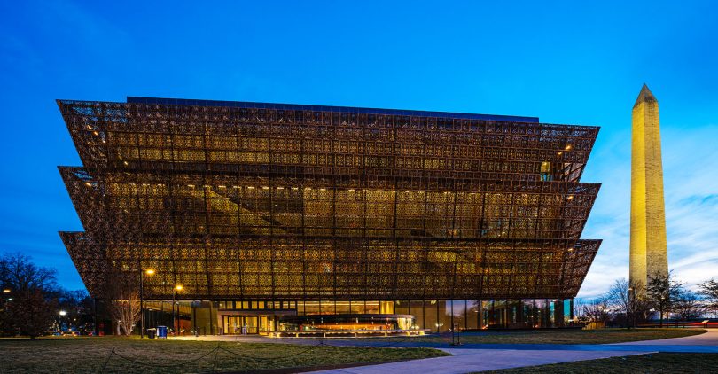 Washington D.C., USA - February 10, 2023: The National Museum of African American History and Culture at night with the Washington Monument in downtown Washington DC.