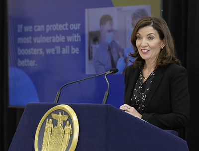 Governor Hochul stands at podium with presentation slide behind her