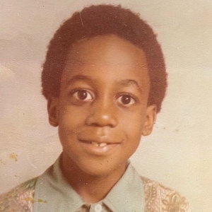 A headshot picture of a young Sen. Raphael Warnock smiling at the camera