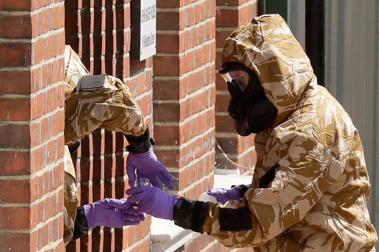 Specialist team members in military protective suits use a jar in the front doorway as they search the fenced-off John Baker House for homeless people on Rollestone Street in Salisbury, England. (Matt Dunham/AP)