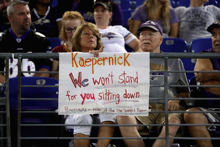 A fan sits behind a sign referring to Colin Kaepernick during a Redskins-Ravens game in Baltimore last year. (Rob Carr/Getty Images)