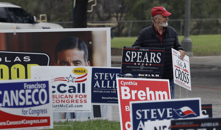 Jim Mathis places a campaign sign near a polling site in San Antonio. The Texas primaries are Tuesday. (Eric Gay/AP)