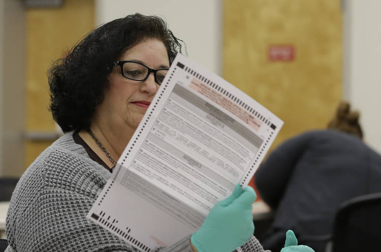 Beverly Darm, an election clerk at the Sacramento County Registrar of Voters, inspects a mail-in ballot in Sacramento. More than 1.4 million Californians have already voted absentee in the state's primary, which could have the highest ever rate of vote by mail. (Rich Pedroncelli/AP)