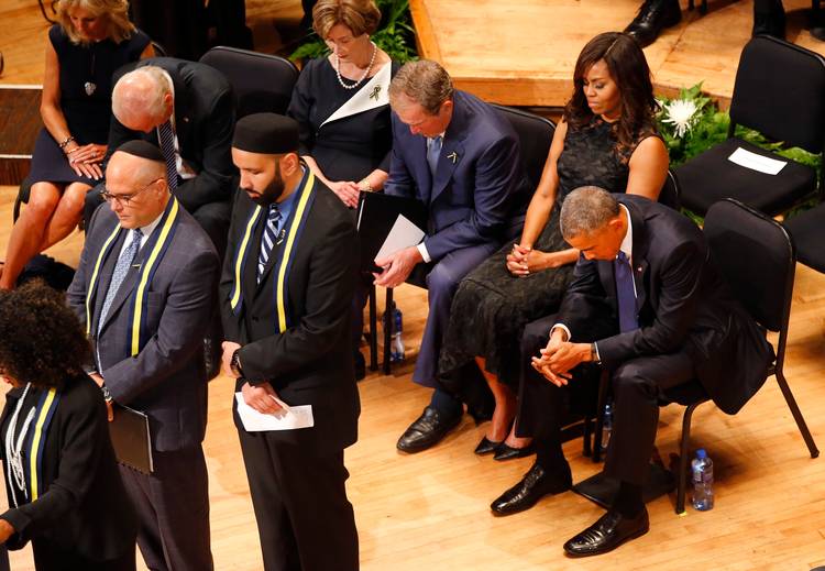 Barack and Michelle Obama, along with George and Laura Bush and Joe and Jill Biden, bow their heads in prayer during an interfaith memorial service in 2016 for five fallen police officers in Dallas. (Tom Fox/The Dallas Morning News via AP)