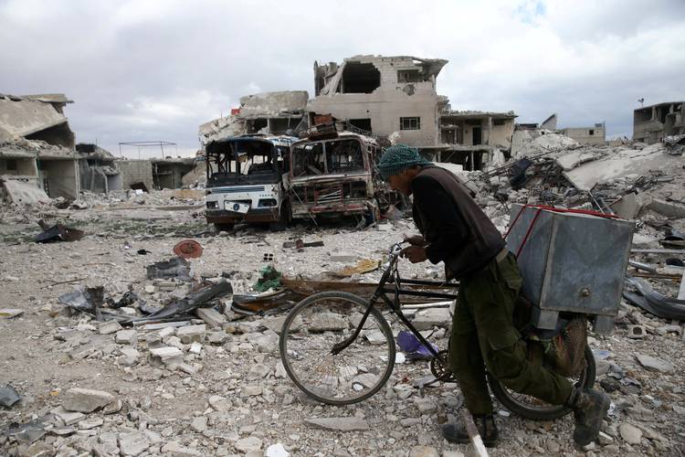 A man walks with his bicycle in the besieged Syrian town of Douma. (Bassam/Reuters)