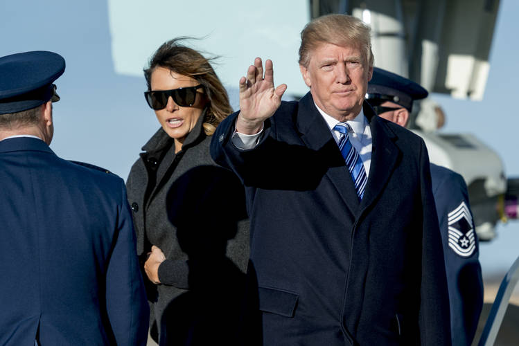 The president, accompanied by the first lady, waves to members of the media as they arrive Saturday at Andrews Air Force Base. (Andrew Harnik/AP)