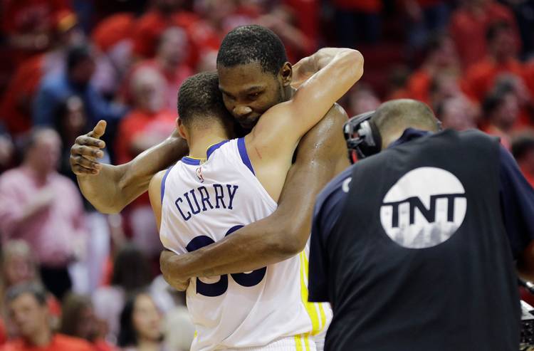 Warriors forward Kevin Durant, right, hugs teammate Stephen Curry, left, after they defeated the Rockets last night. (David J. Phillip/AP)