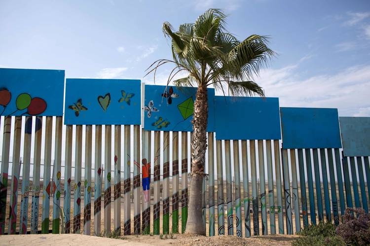 The U.S.-Mexico border wall has been painted by members of the Brotherhood Mural organization. (Guillermo Arias/AFP/Getty Images)