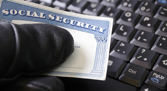 Gloved hand holding Social Security card over keyboard