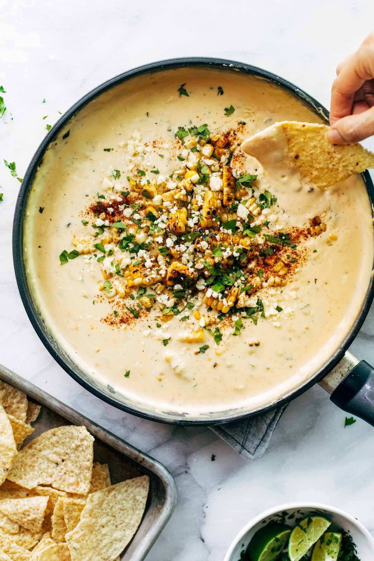 Elote queso in a pan with a chip.