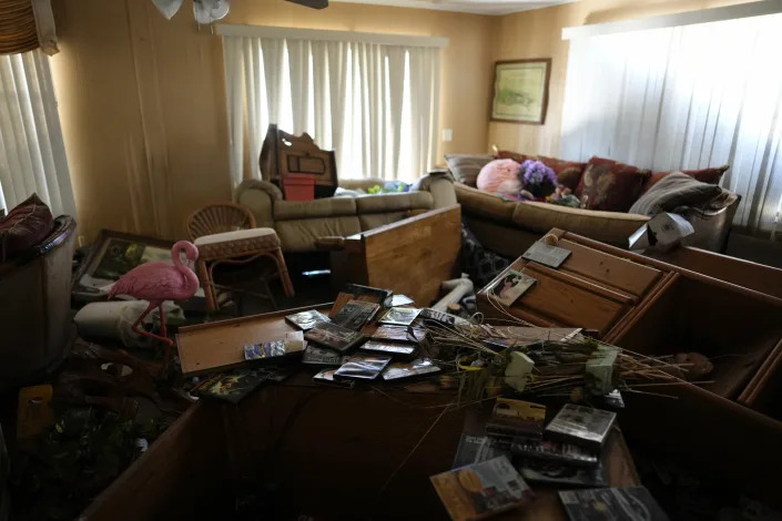 Furniture and personal items lie jumbled in the living room of Nita Ross, 79, as she returns to her mobile home for the first time since the passage of Hurricane Ian, at the Sunshine Mobile Home Park in Fort Myers, Fla., Saturday, Oct. 1, 2022. Ross' home stayed on its foundations, unlike those of some of her neighbors, but storm flooding almost to the height of the ceiling destroyed most of her possessions and household items. (AP Photo/Rebecca Blackwell)