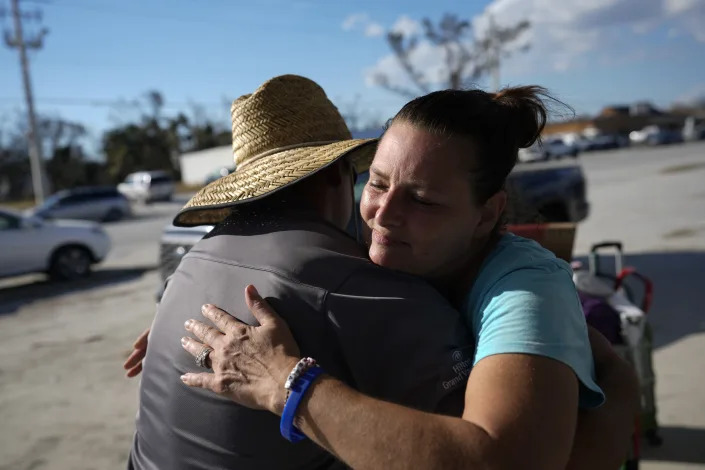 Heide Haydu hugs a friend as they part ways after evacuating from Estero Island in Fort Myers Beach, Fla., Saturday, Oct. 1, 2022, three days after Hurricane Ian bore down on the barrier island. Haydu lives in the region and was staying at a beachfront resort with her husband on Estero Island when the storm hit. (AP Photo/Rebecca Blackwell)